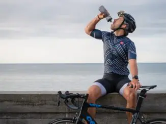 woman in black and white stripe tank top and black shorts sitting on brown wooden fence hydration